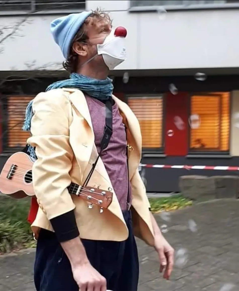 Klinik-Clown mit roter Nase und Maske steht im Freien