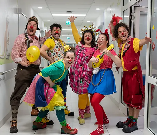 Bunte Klinik-Clowns bringen Freude in ein Krankenhaus, während sie fröhlich in einem Flur posieren